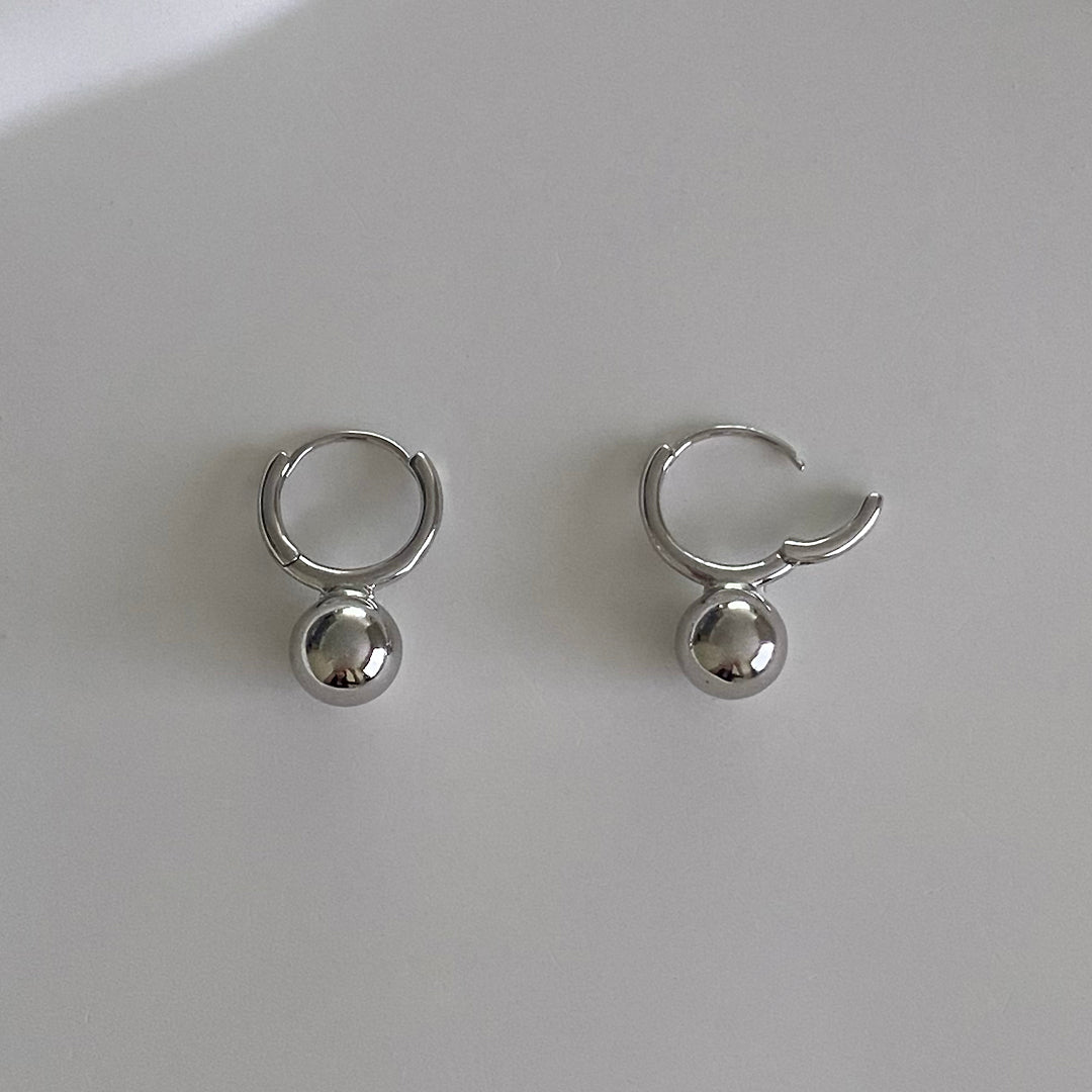 Detail view of silver mini ball huggies with one hoop earring open