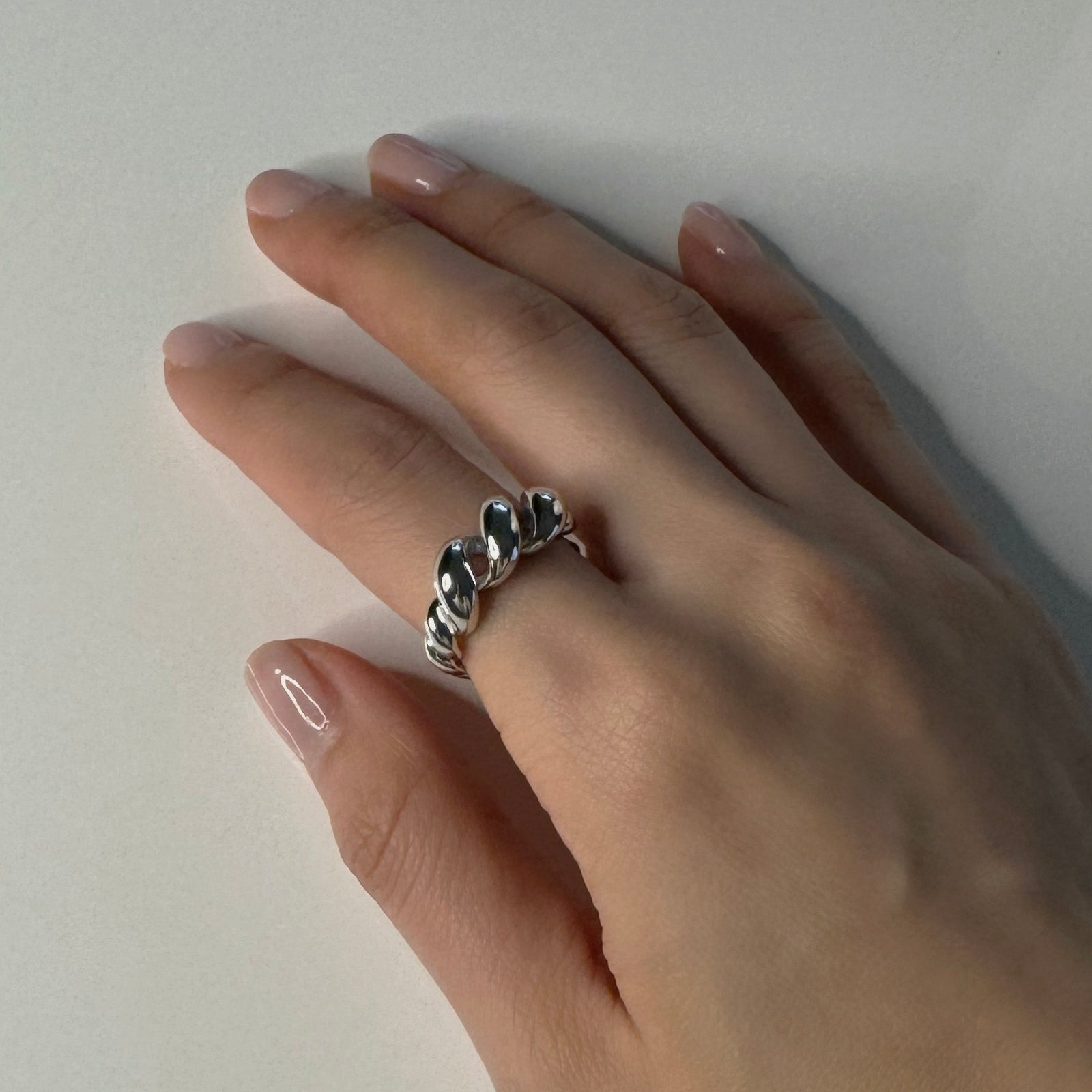 hand view of twisted ring. This ring is made with sterling silver and rhodium plated.