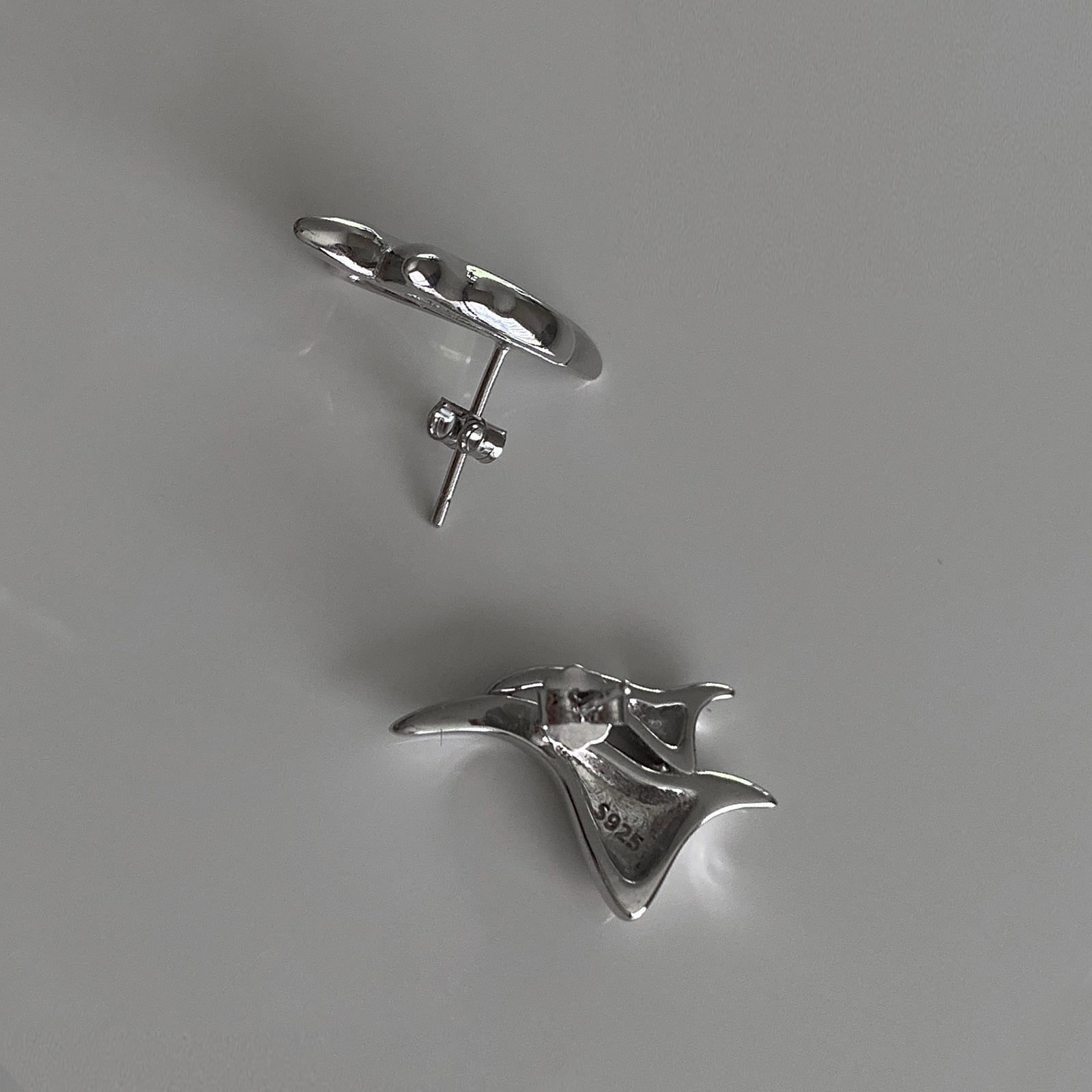 A close up look of our silver studs called Flame Studs showing the push-back closure and a close-up of our S925 stamp on the inside of the stud.