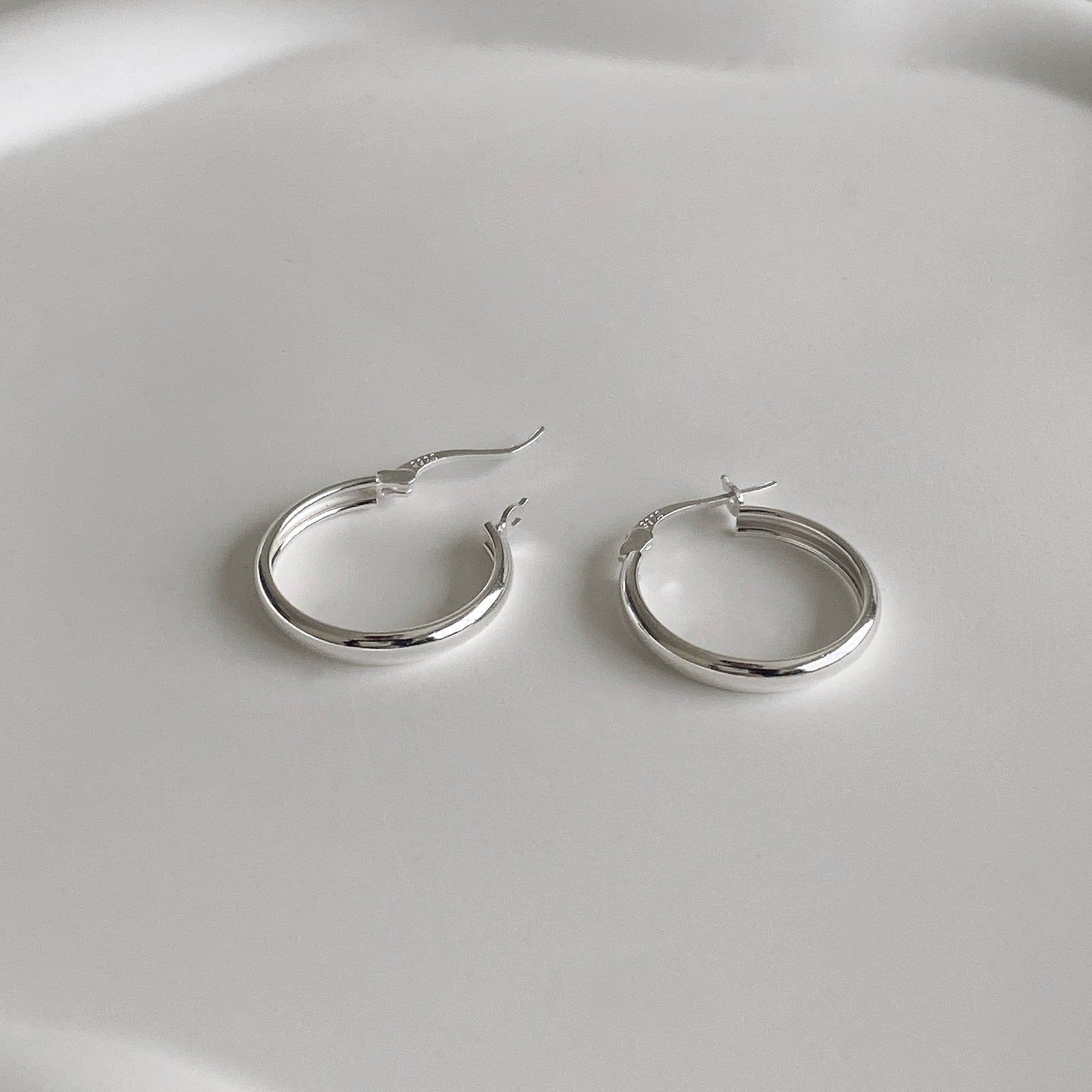 Side view of Jane Hoops 20mm are classic hoop earrings with a latch back for closure. It's made of 925 sterling silver with a shiny smooth finish. Perfect hoop earrings for everyday.