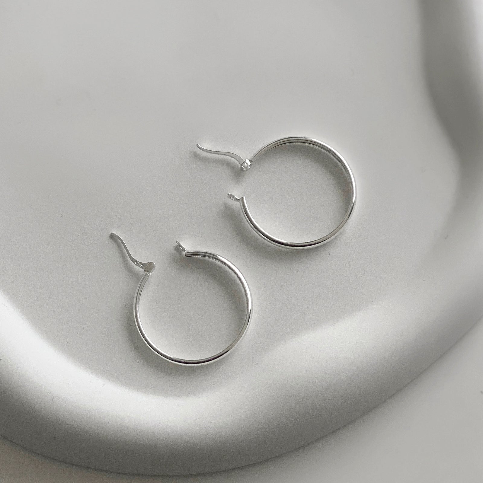 Open view of Jane Hoops size 30mm. These are classic hoop earrings with a latch back for closure. Has a S925 stamp on the latch. These hoop earrings are made of 925 Sterling Silver and has a smooth and shiny finish.