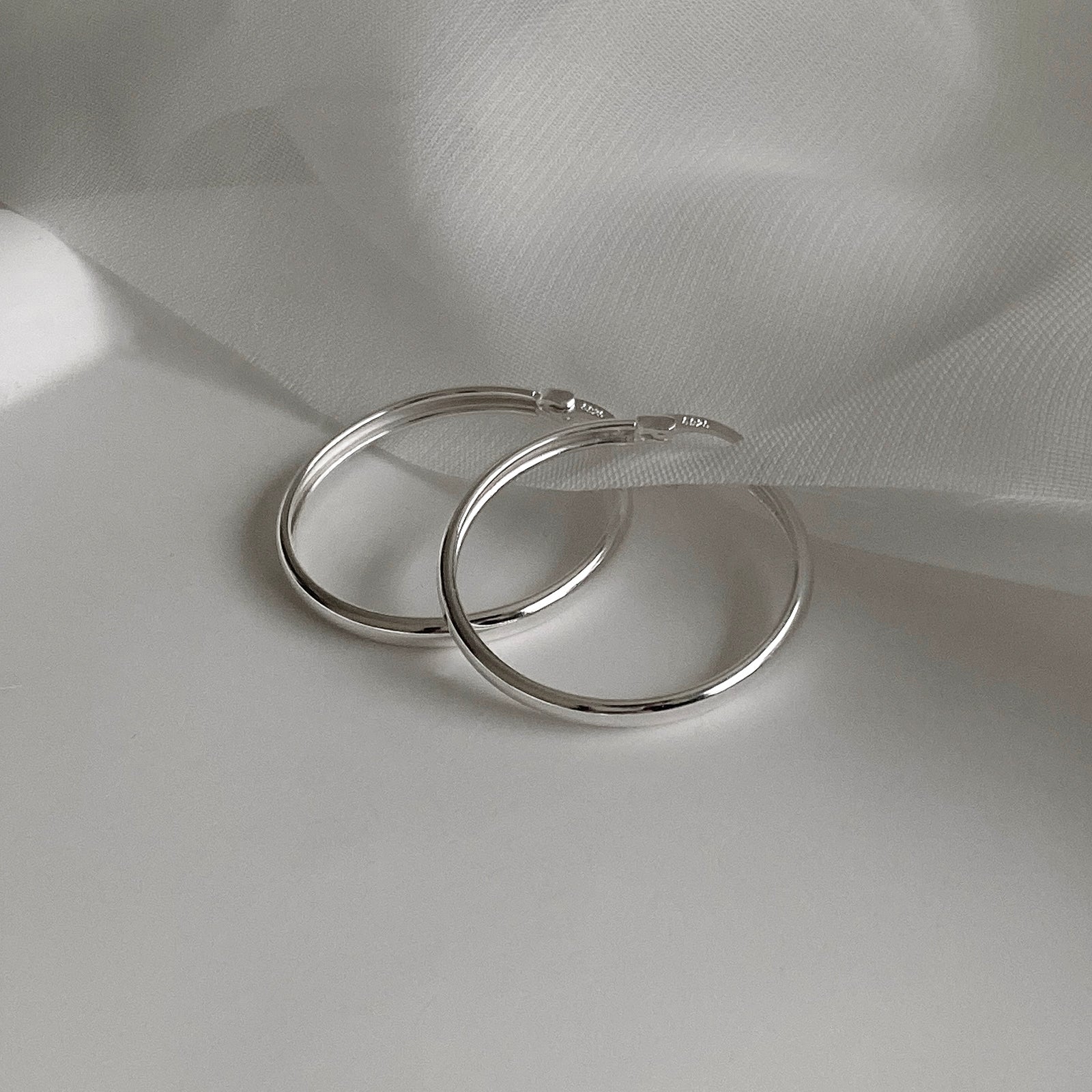 Detail View of Jane Hoops size 30mm. These are classic hoop earrings with a latch back for closure. Has a S925 stamp on the latch. These hoop earrings are made of 925 Sterling Silver and has a smooth and shiny finish.