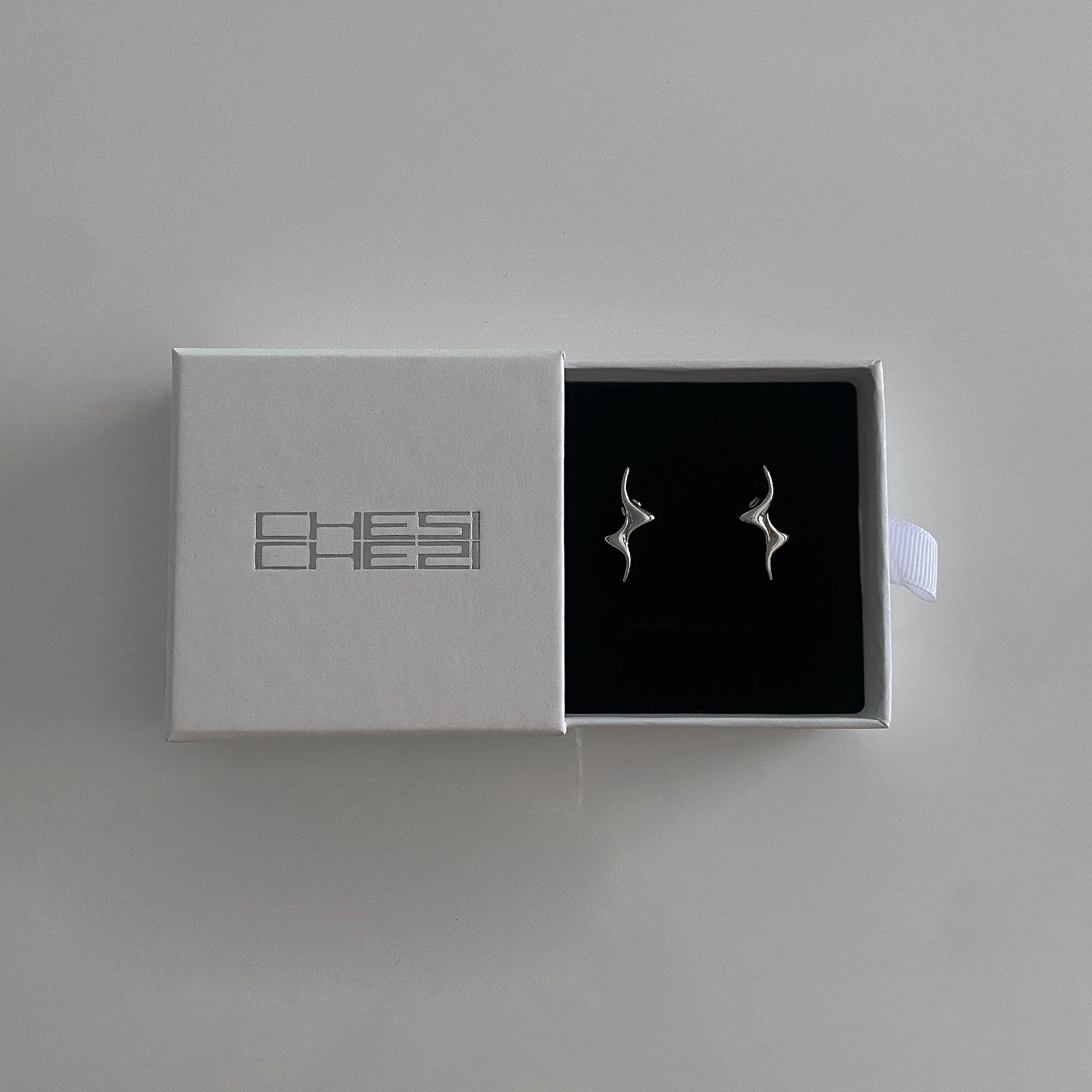 These cool Swirly Bolt Studs are shown in our Chesi Gift Box. Has a swirly lightning bolt design made of 925 silver with rhodium plating for extra protection and strength.